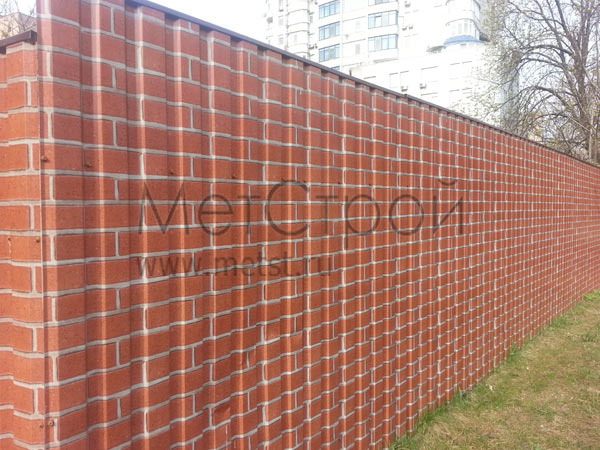 Забор из профнастила с покрытием printech под 
красный кирпич (red brick). Сверху установлены 
металлические планки.